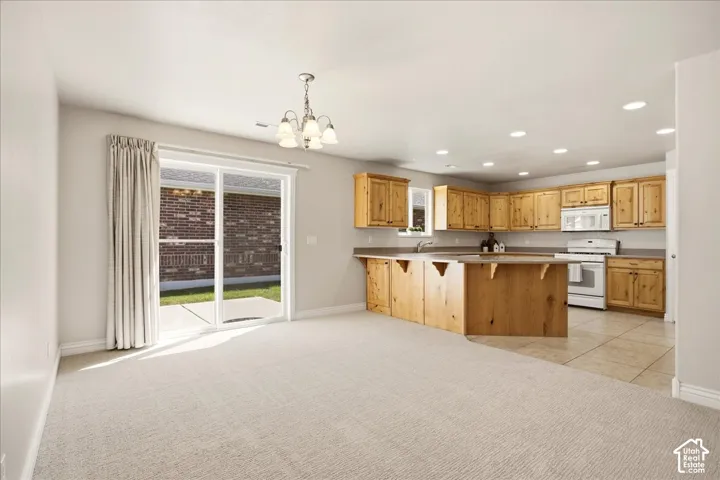 Kitchen featuring wood cabinetry, white appliances, and a central island with bar seating