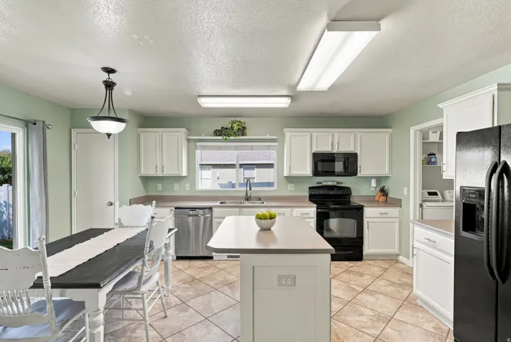 Kitchen featuring white cabinetry, black appliances, a central island, and tiled flooring