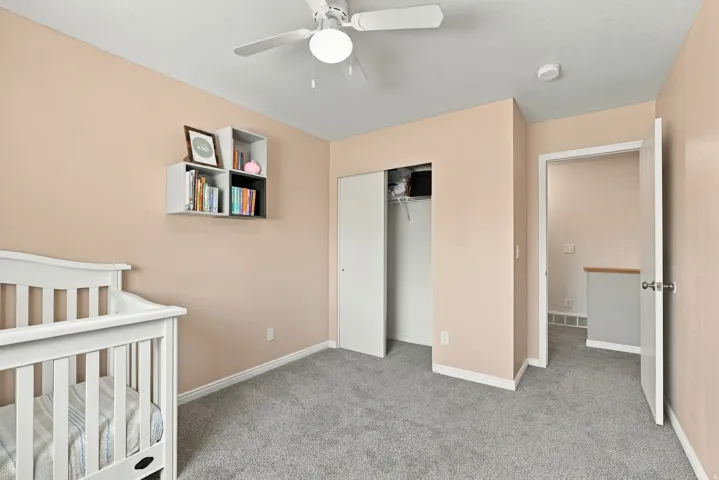 Plush carpet flooring, a built-in closet with sliding doors, and a ceiling fan with integrated lighting