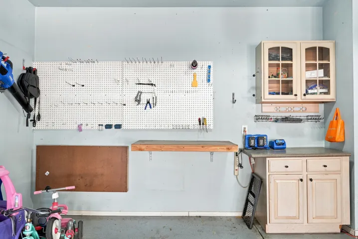Built-in cabinetry with glass-front uppers, a functional countertop, and a wall-mounted pegboard for organization