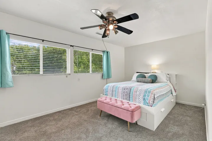 Carpeted room featuring multiple windows, a ceiling fan with integrated lighting, and neutral wall tones