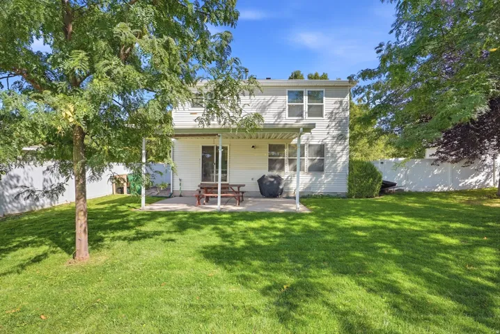 Expansive backyard featuring a manicured lawn, a concrete patio, a covered porch, and privacy fencing