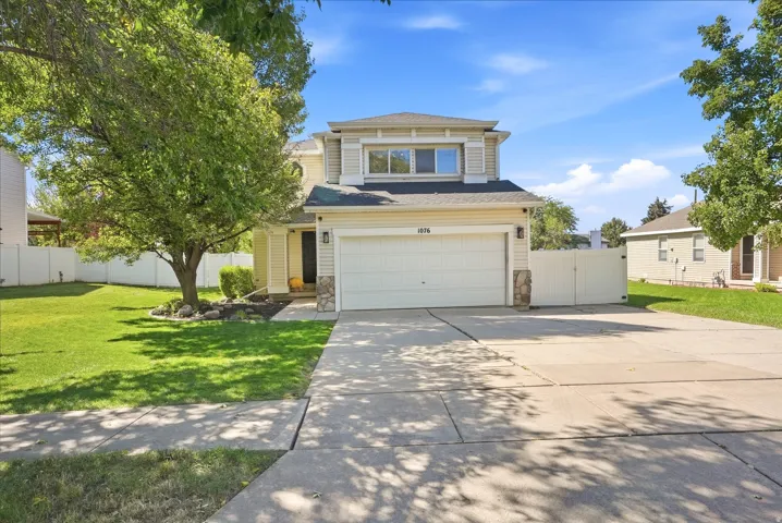 Two-story exterior with siding and stone accents, a two-car garage, established front yard landscaping, and a concrete driveway