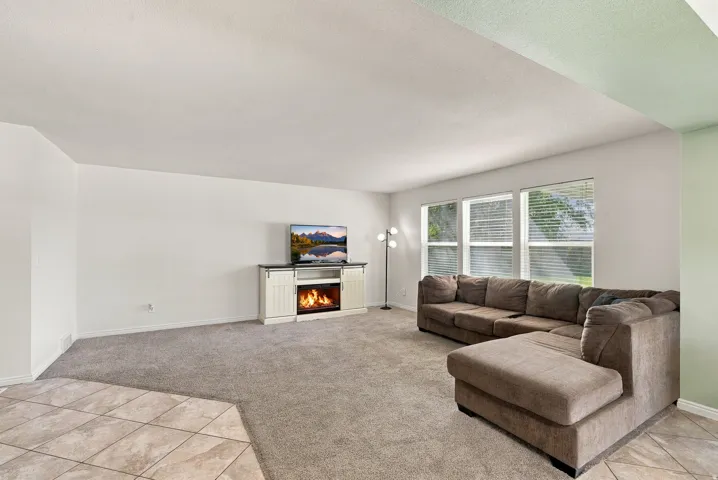 Carpeted living area with tile flooring accent and multiple windows