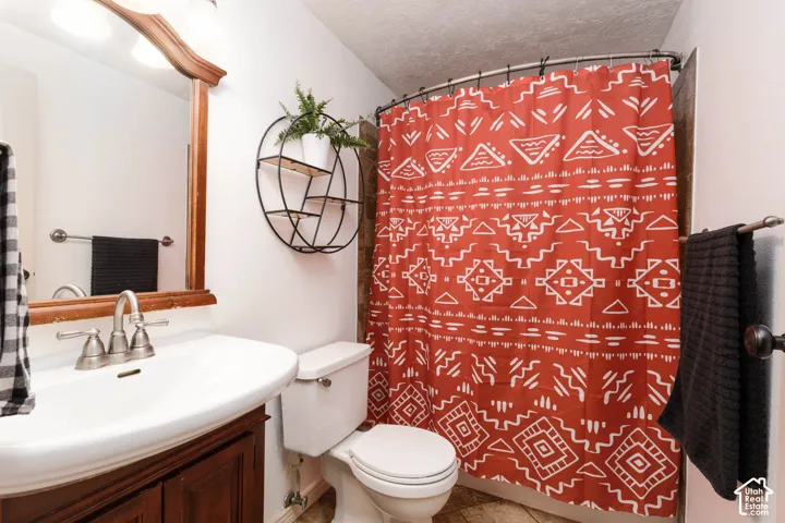 White pedestal sink with a dual-handle faucet, wood-finish vanity, and a framed mirror with integrated lighting