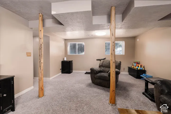 Expansive carpeted room featuring unique rustic wood columns, neutral wall tones, and recessed ceiling details
