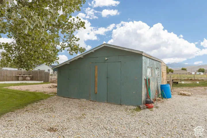 Detached storage building with dual access doors, gravel drive, and adjacent grassy area