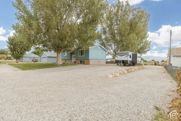 Spacious gravel driveway with a decorative rock border and mature trees