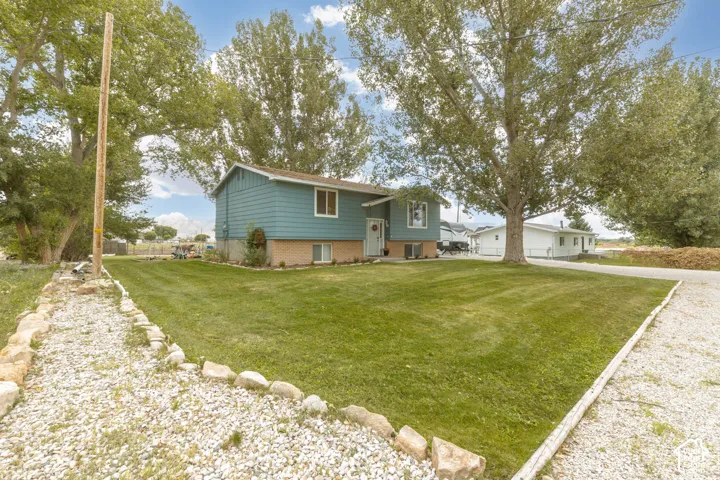 Two-story residence featuring a blue siding exterior, brick foundation, and a gravel driveway