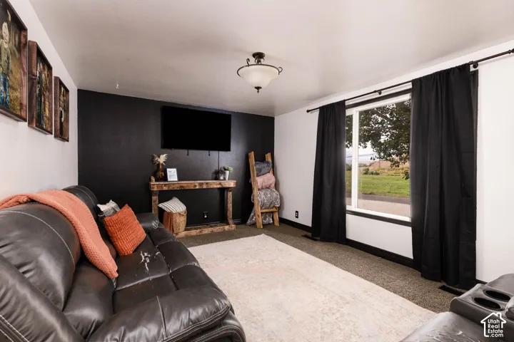 Wall-mounted television with a dark accent wall, a wide window with dark trim, and a ceiling-mounted light fixture