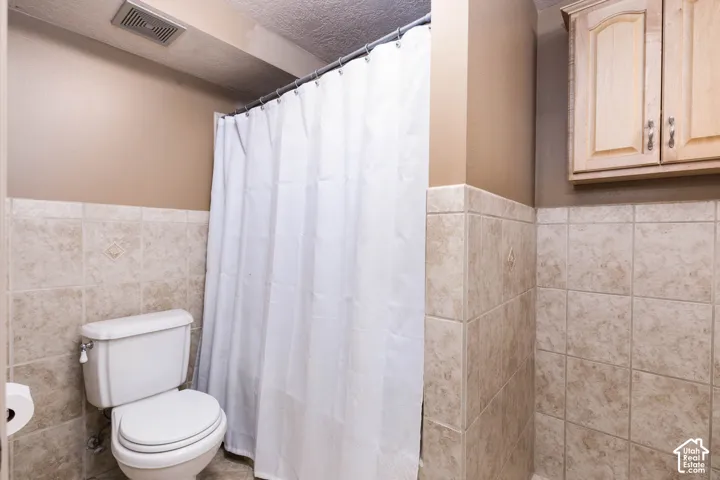 Neutral-toned wall tiling, built-in storage cabinetry, and a white toilet