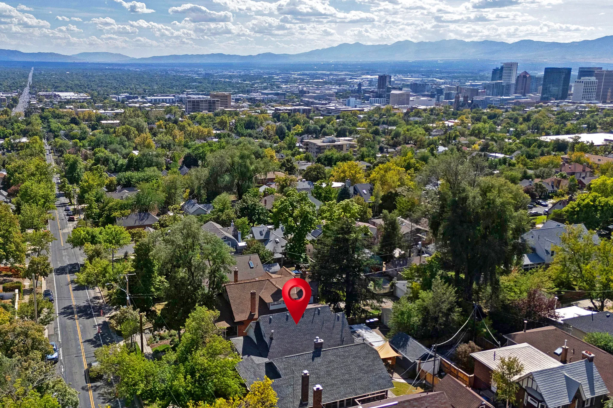 Residential property with mature trees, surrounded by an urban landscape and distant mountains