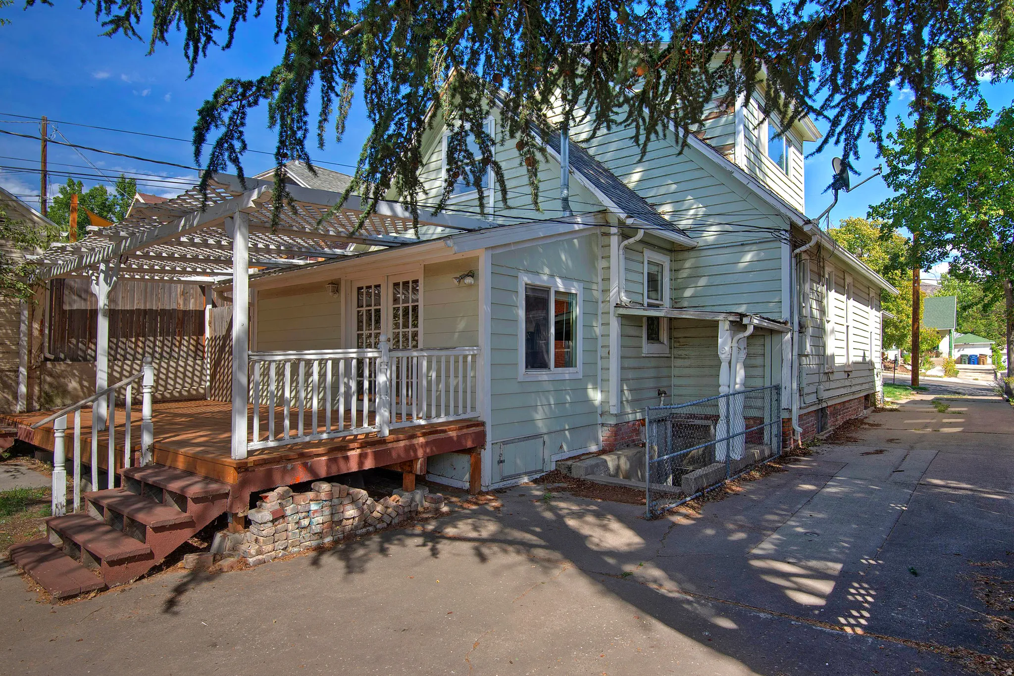 Exterior featuring light-colored siding, a multi-level wood deck with steps, a white pergola structure, and white French doors