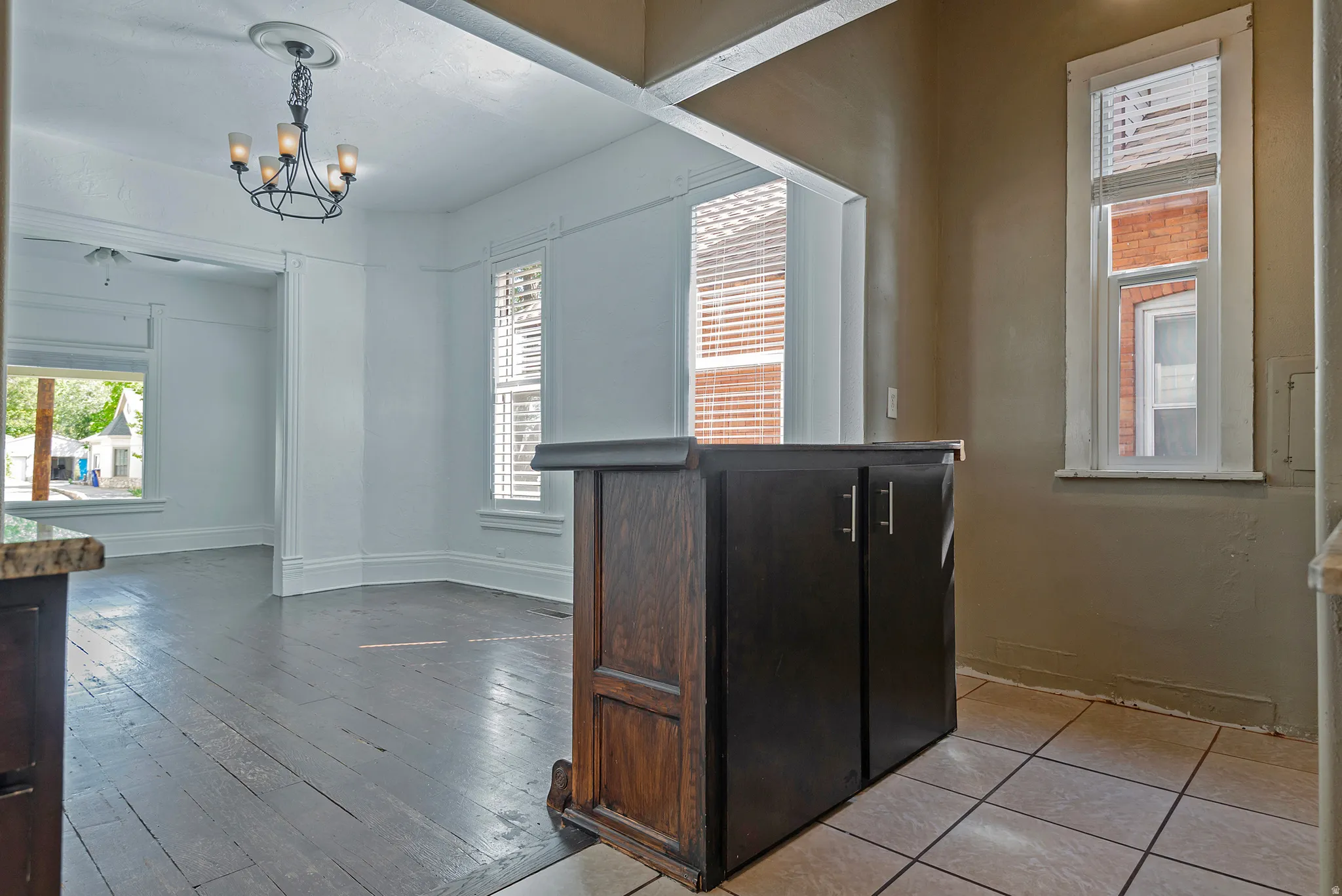 Built-in wood-finish cabinetry, tile flooring, wood-finish flooring, white trim, and a decorative ceiling light fixture