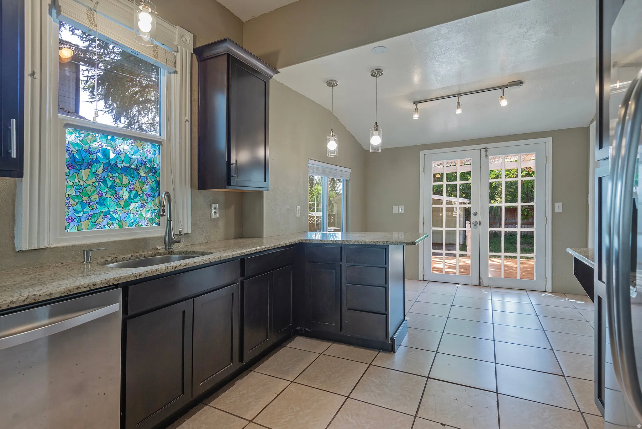 Dark wood-finish cabinetry with light-toned countertops, a stainless steel sink, and an integrated dishwasher