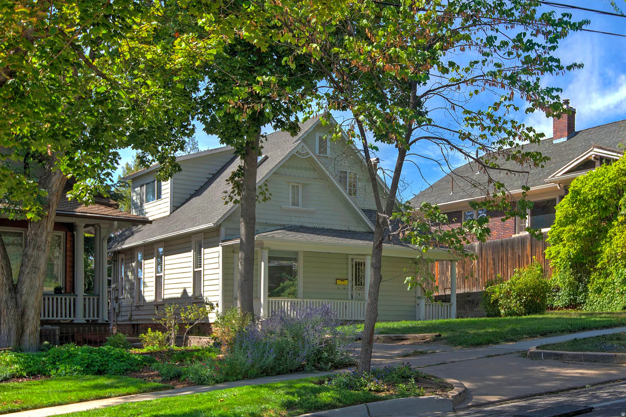 Light green siding exterior with a front porch, white porch railing, and dormer windows