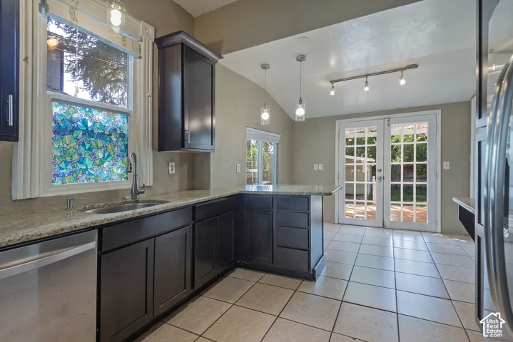 Dark wood-finish cabinetry with light-toned countertops, a stainless steel sink, and an integrated dishwasher