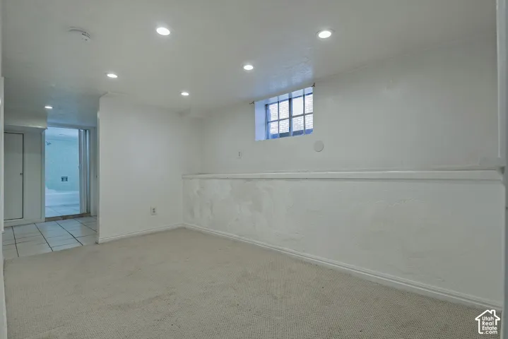 Recessed ceiling lighting, textured wall finish, and a window with security bars