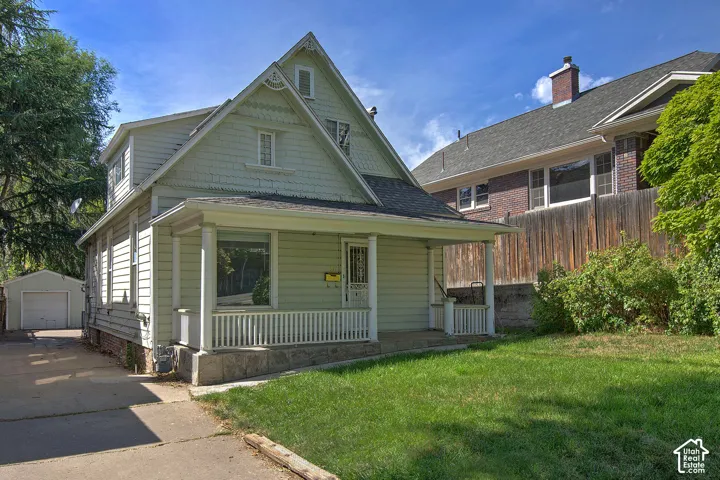 Gabled roofline, front porch, detached garage, established lawn, and wood privacy fencing