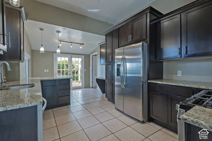 Contemporary kitchen featuring dark wood-finish cabinetry, granite-style countertops, stainless steel appliances, and tile flooring