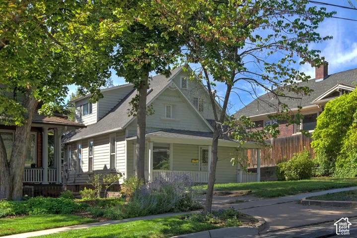 Light green siding exterior with a front porch, white porch railing, and dormer windows
