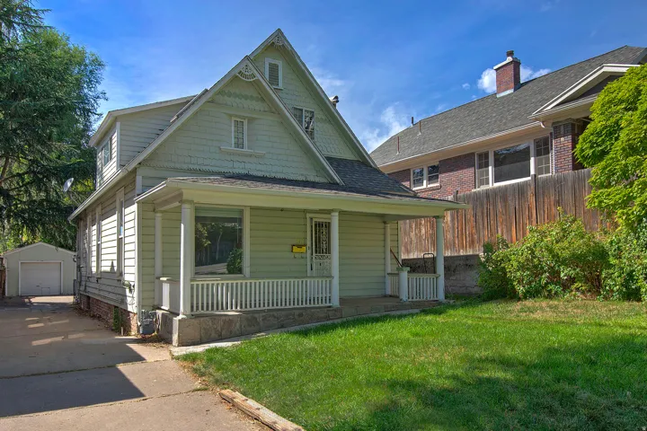 Gabled roofline, front porch, detached garage, established lawn, and wood privacy fencing