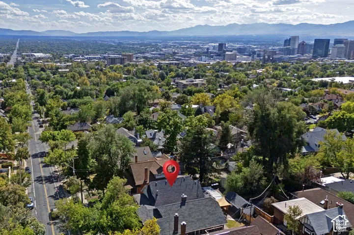 Residential property with mature trees, surrounded by an urban landscape and distant mountains