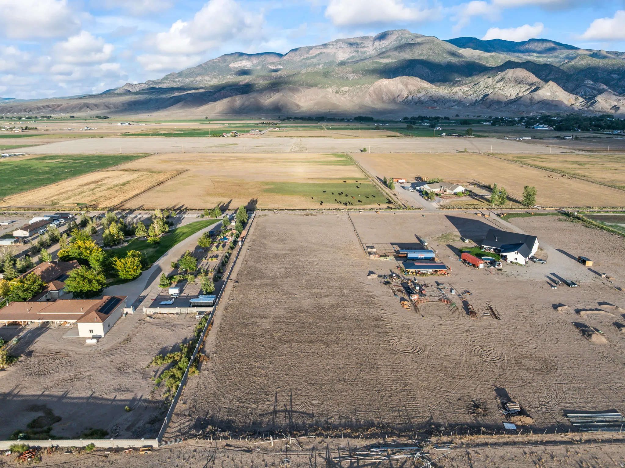 Expansive land parcel featuring multiple structures, open fields, and mountain scenery