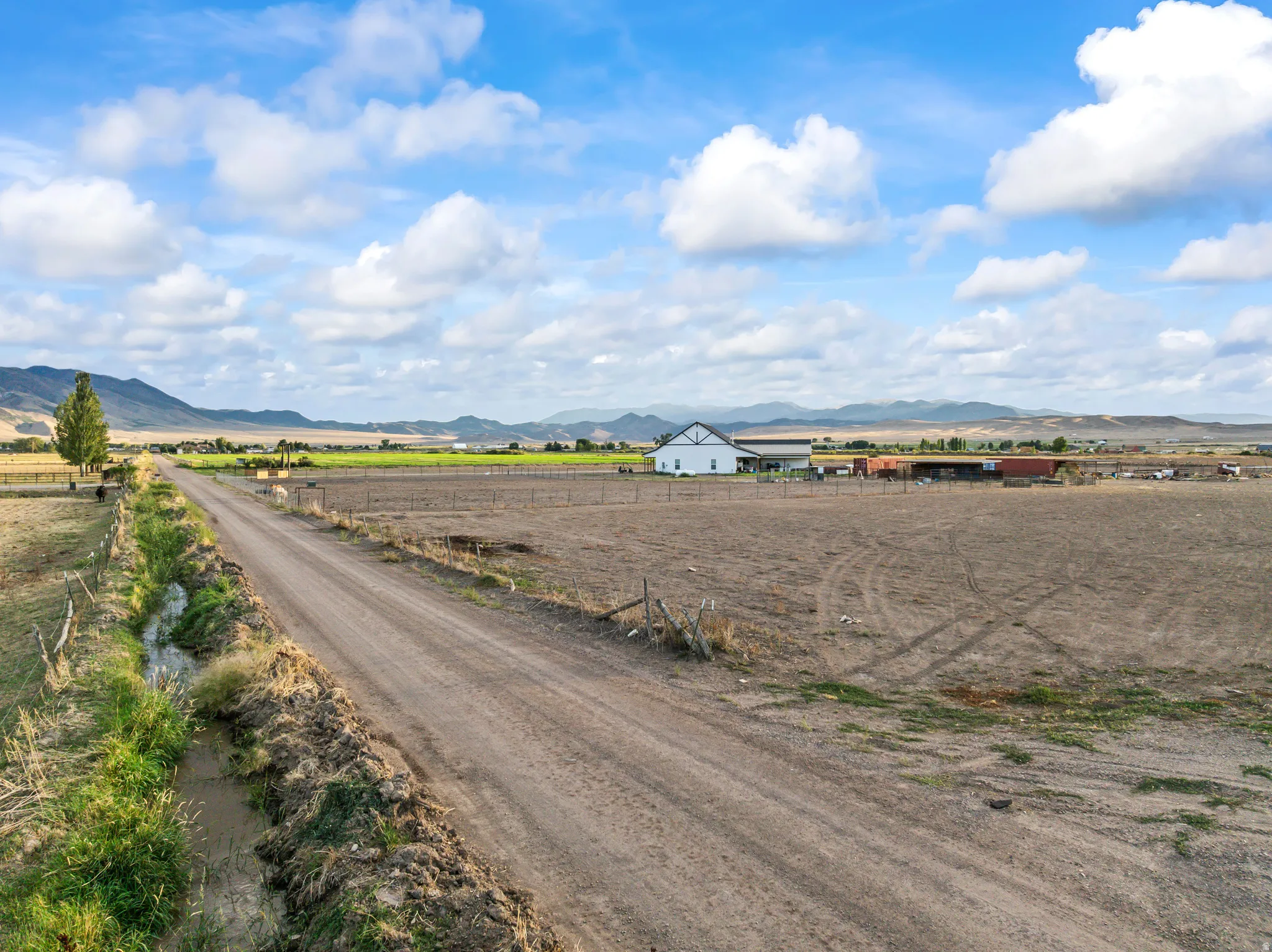 Expansive agricultural land featuring a dirt road and a drainage ditch