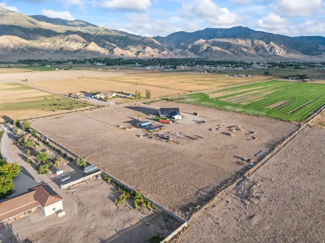 Expansive property with distant mountain range, agricultural fields, and a single-story residence