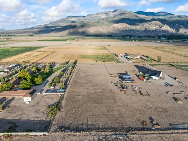 Expansive land parcel featuring multiple structures, open fields, and mountain scenery