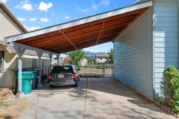 Attached carport featuring a concrete driveway and exposed wood ceiling