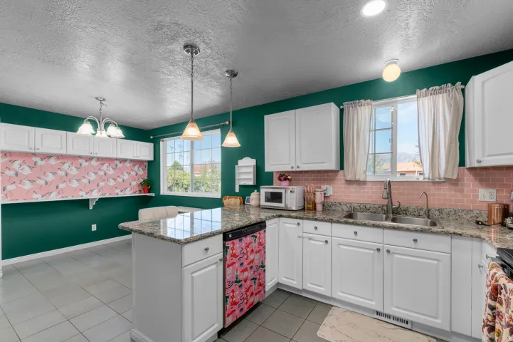 Kitchen featuring white cabinetry, granite-style countertops, a subway tile backsplash, a kitchen island with pendant lighting, and tile flooring