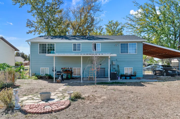 Two-story exterior with light blue siding, a covered patio, and an attached carport