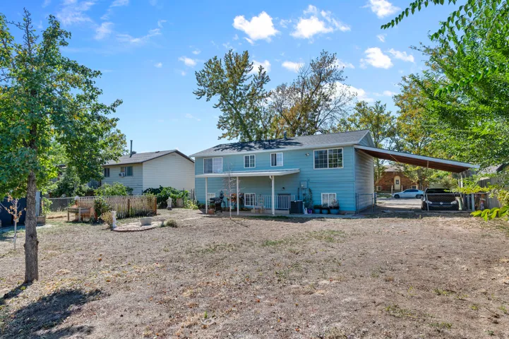 Two-story exterior with light blue siding, a covered patio, and an extended carport