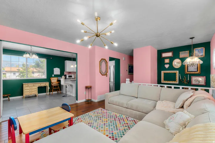 Open-concept living area with hardwood flooring, a contemporary sputnik chandelier, and a built-in railing