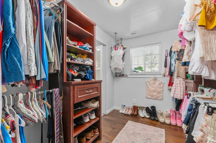 Custom closet system featuring wood-finish cabinetry, built-in shelving, and a window for natural light