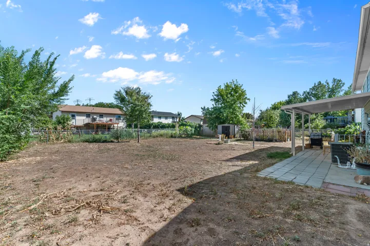 Expansive outdoor area featuring a concrete patio, covered patio structure, and a detached shed
