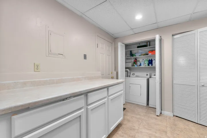 Built-in cabinetry with counter space, laundry closet with appliances, and tile flooring