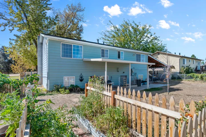Rear exterior featuring a covered patio, multiple windows, and a fenced garden area