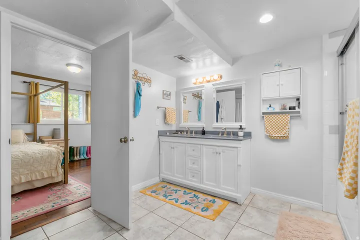 Dual vanity with white cabinetry, integrated sinks, and individual mirrors