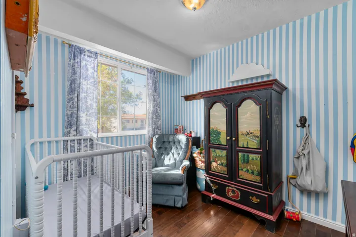 Hardwood-finish flooring, striped wall covering, single window with drapes, and flush mount lighting