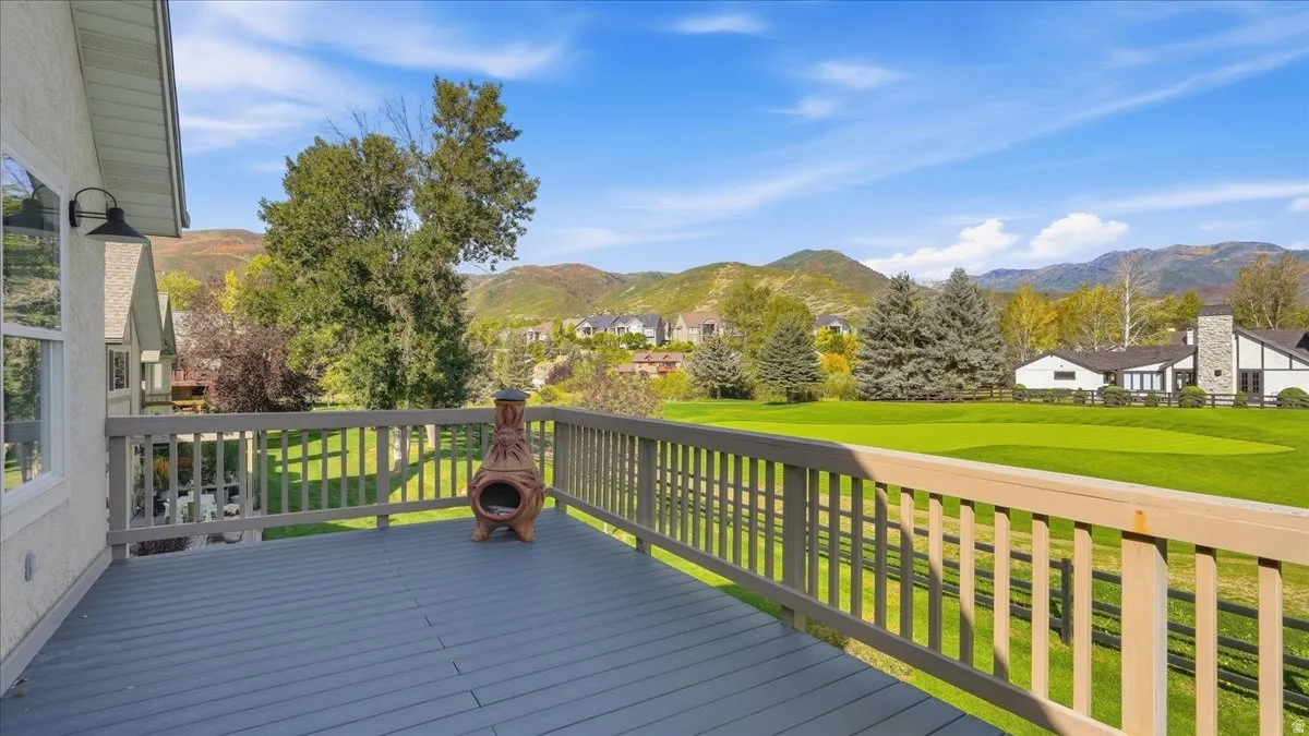 Expansive outdoor deck with wood railing, overlooking a green landscape and distant mountains