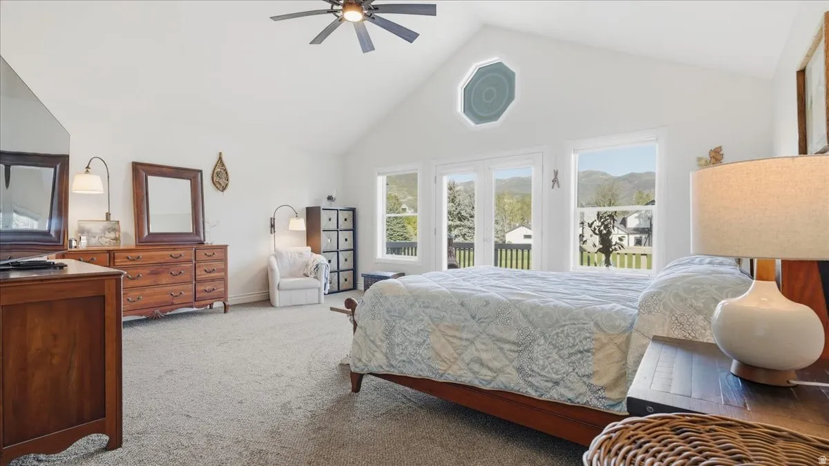 Vaulted ceiling with a ceiling fan, octagon transom window, dual French doors, and carpet flooring