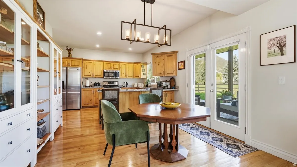 Kitchen featuring wood cabinetry, stainless steel appliances, wood-finish flooring, and vaulted ceilings