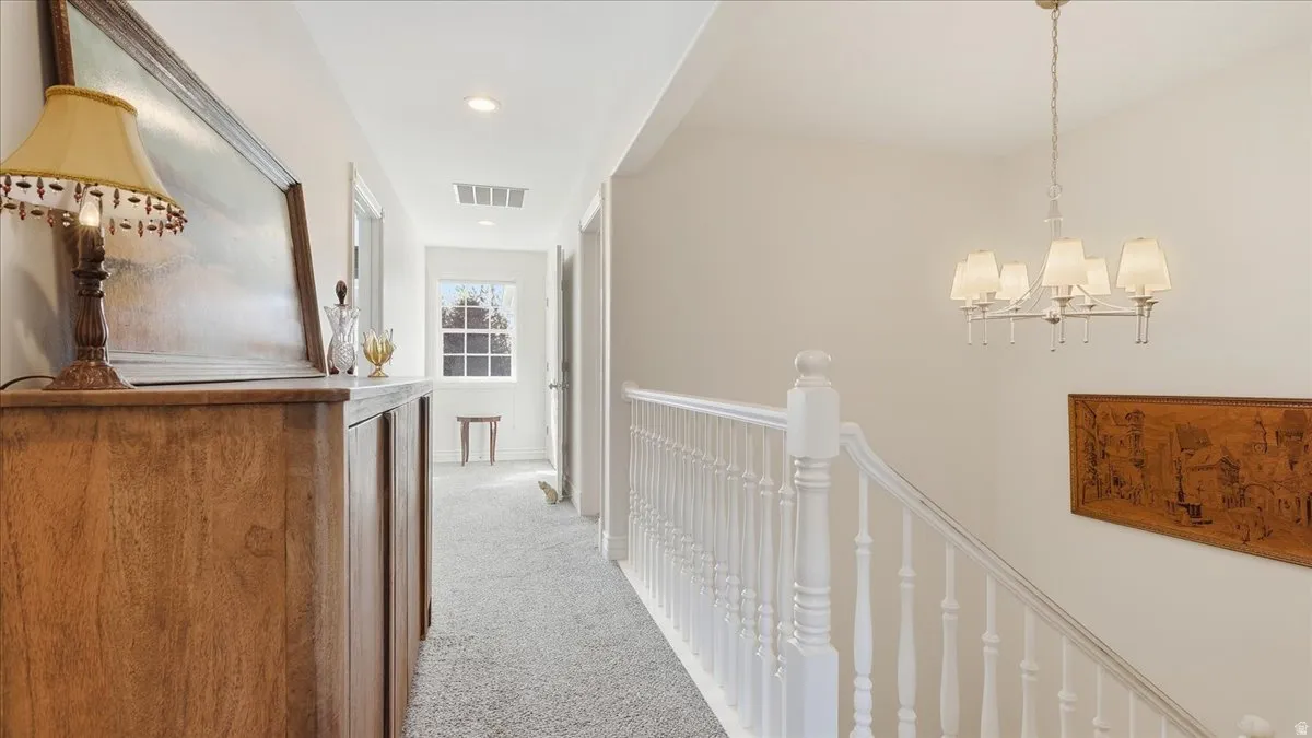 Carpeted hallway with a white spindle railing and a window featuring muntins