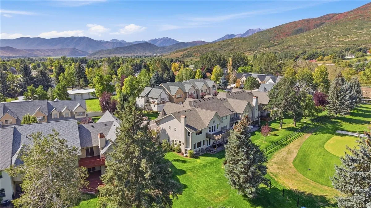 Extensive landscaping with mature trees, green lawn, and a golf course putting green