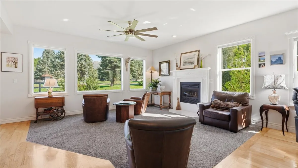 Living area featuring a fireplace with a white mantel, recessed lighting, a ceiling fan, and multiple windows