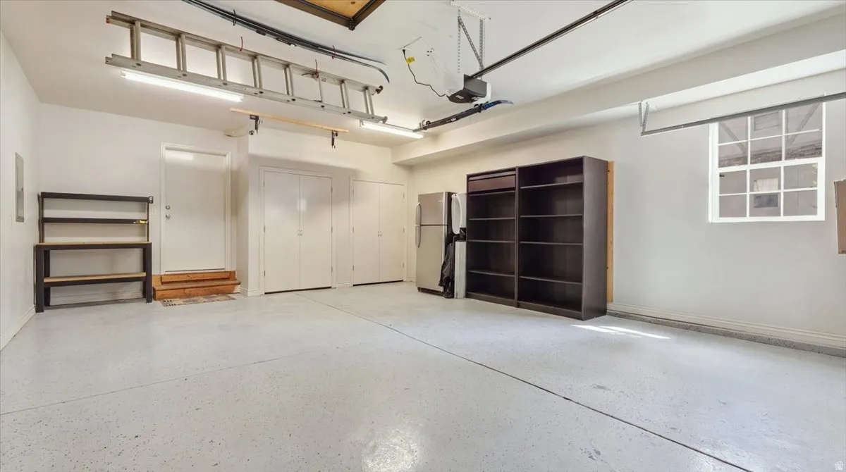 Spacious garage with light grey epoxy flooring, overhead fluorescent lighting, and a multi-pane window