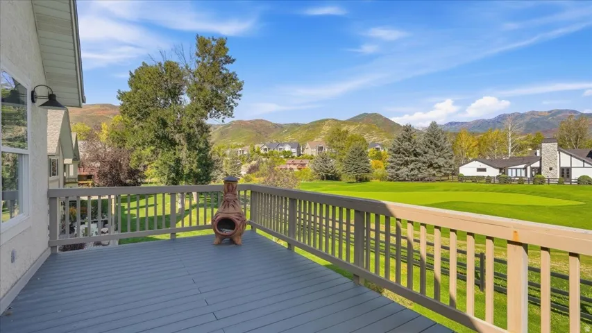 Expansive outdoor deck with wood railing, overlooking a green landscape and distant mountains